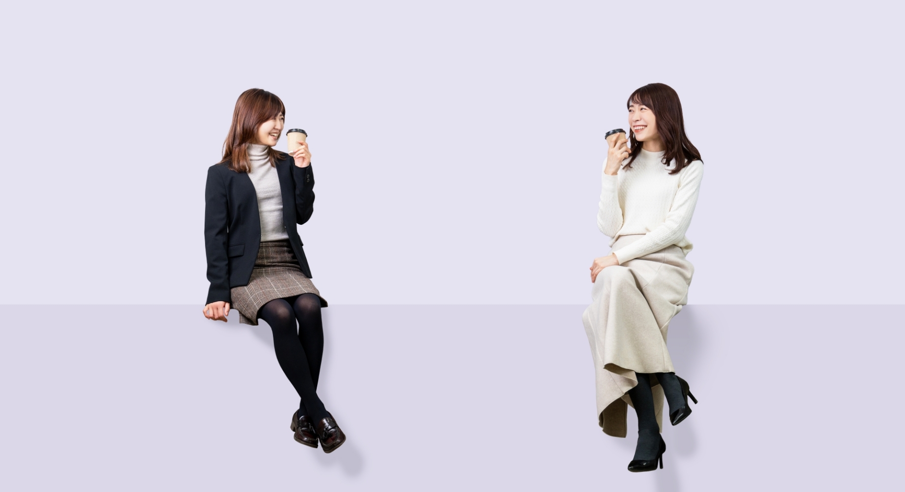 女性二人がコーヒーカップを片手に話している画像